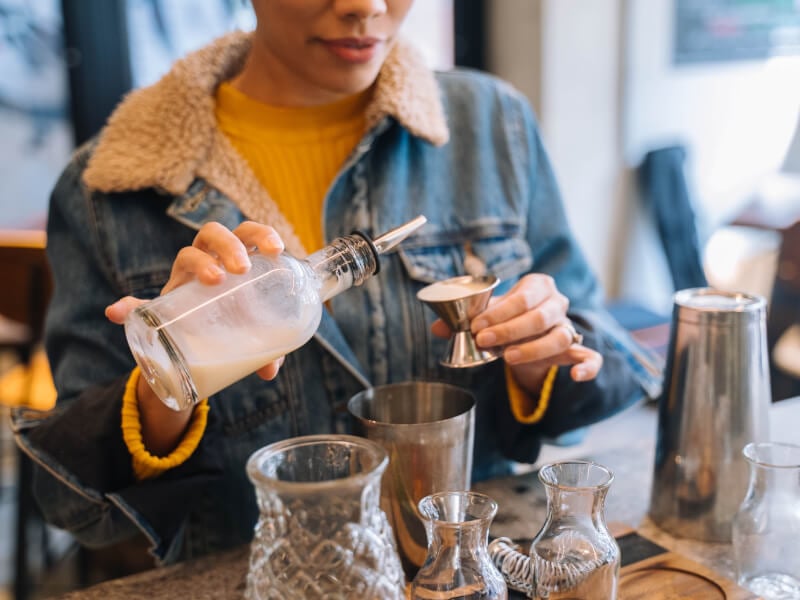 Woman pouring alcohol into a metal jigger